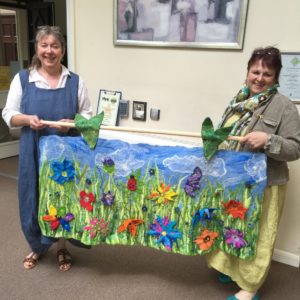 Two adies holding an art painted fabric