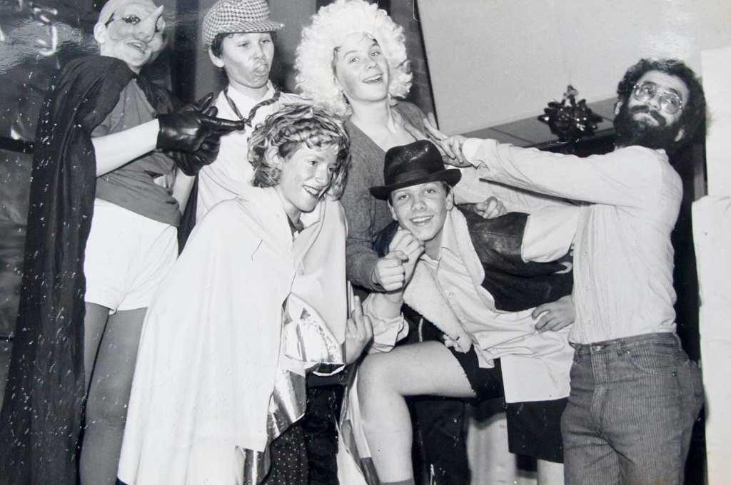 A group of people posing for a photo in various different costumes and wigs.