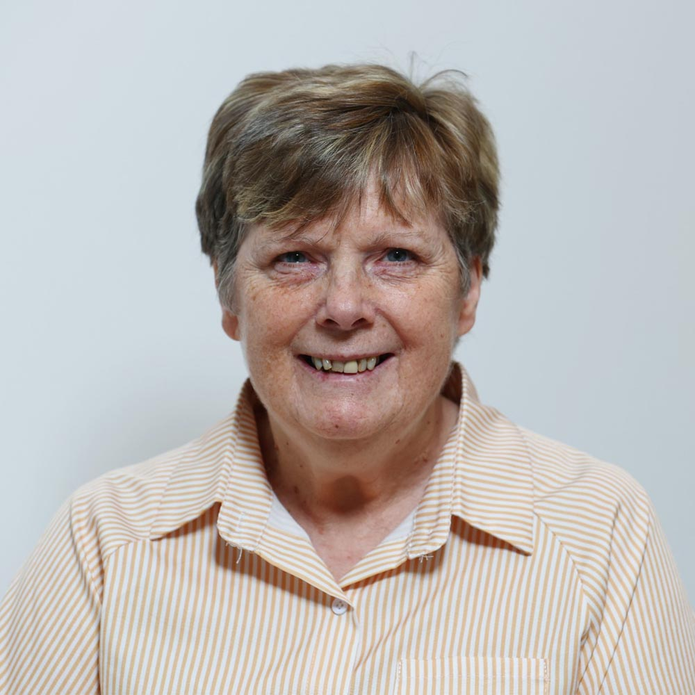 A lady smiling with a vertically striped yellow and white shirt.