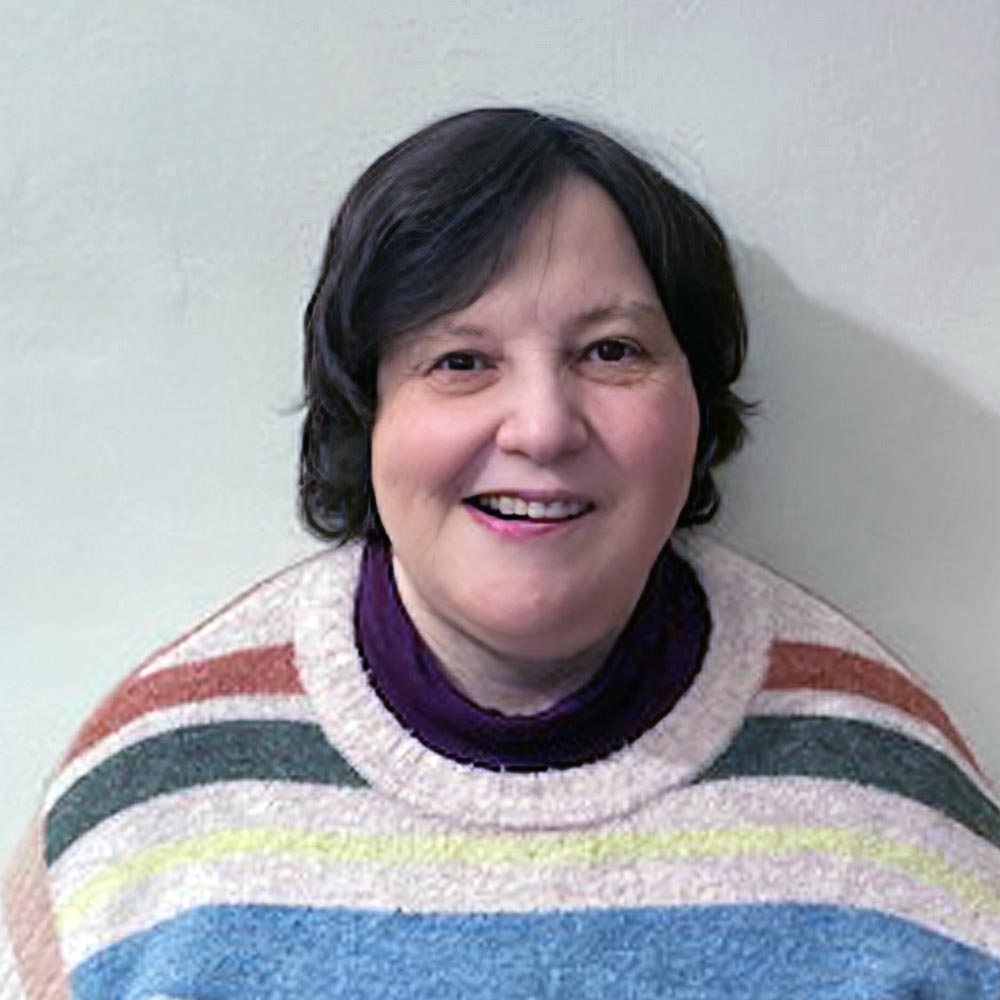A lady smiling with a knitted stripy jumper.