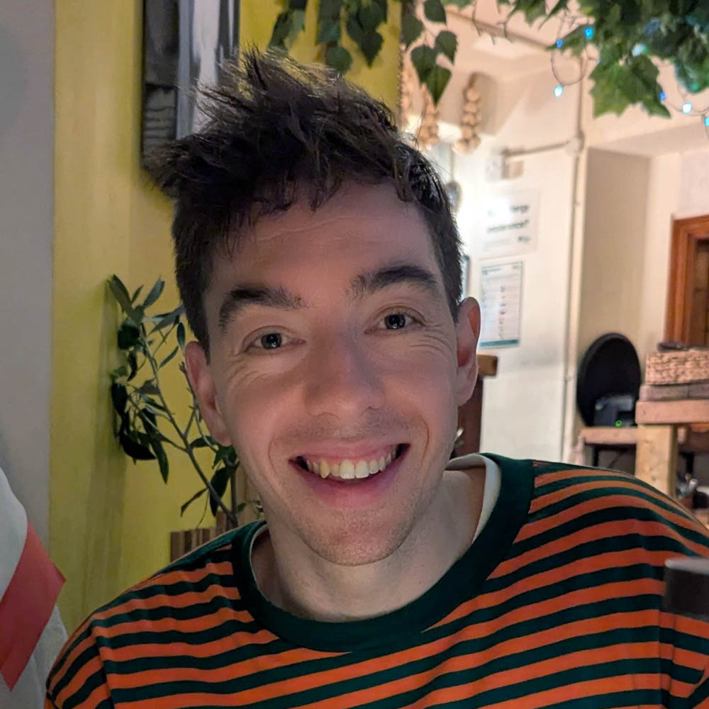 Male smiling with orange and black stripy top.