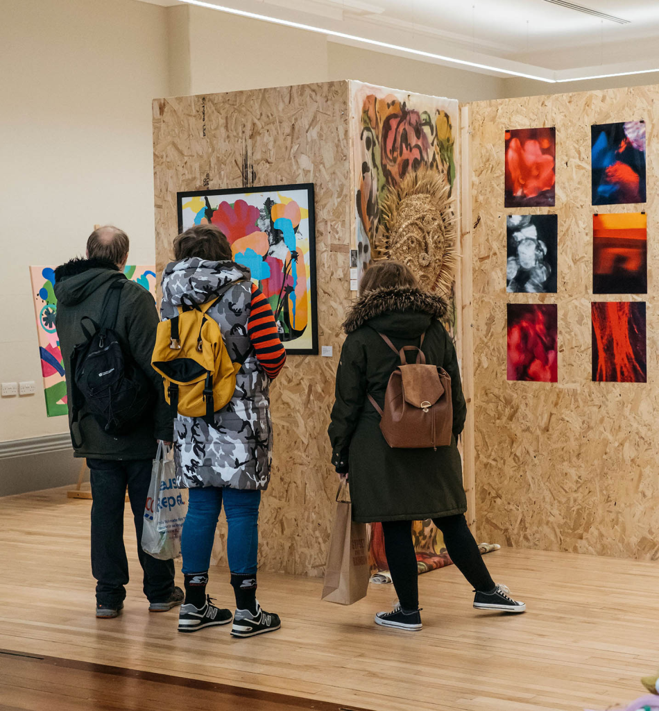 three people looking at artwork at an exhibition