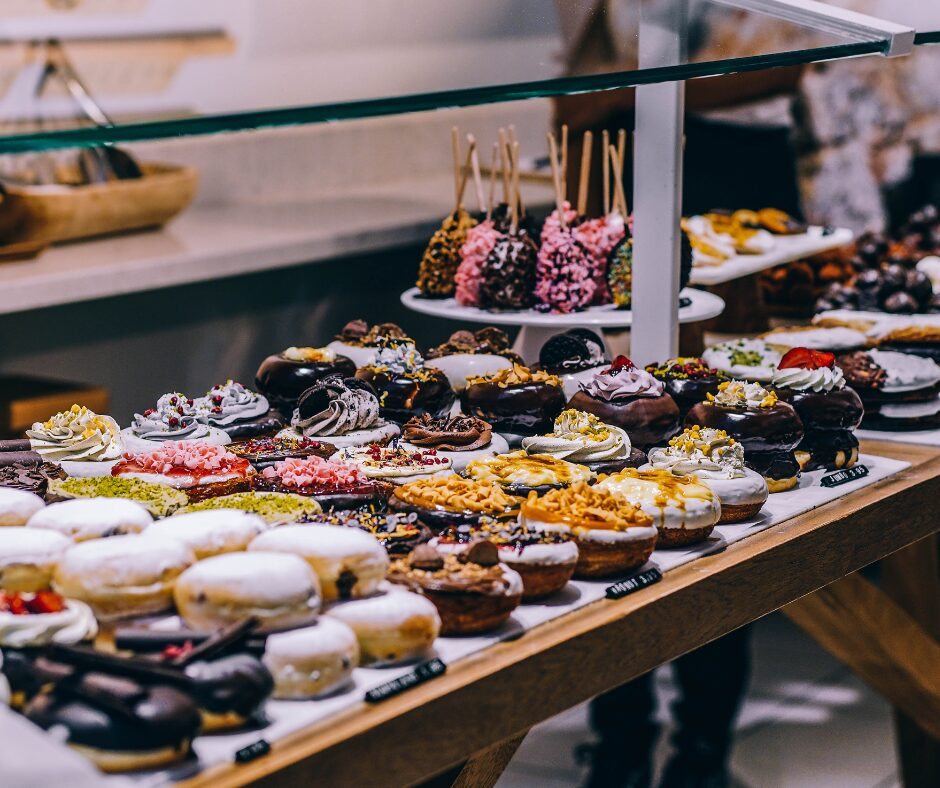 A stand with various baked goods, including cakes and doughnuts, lined up.