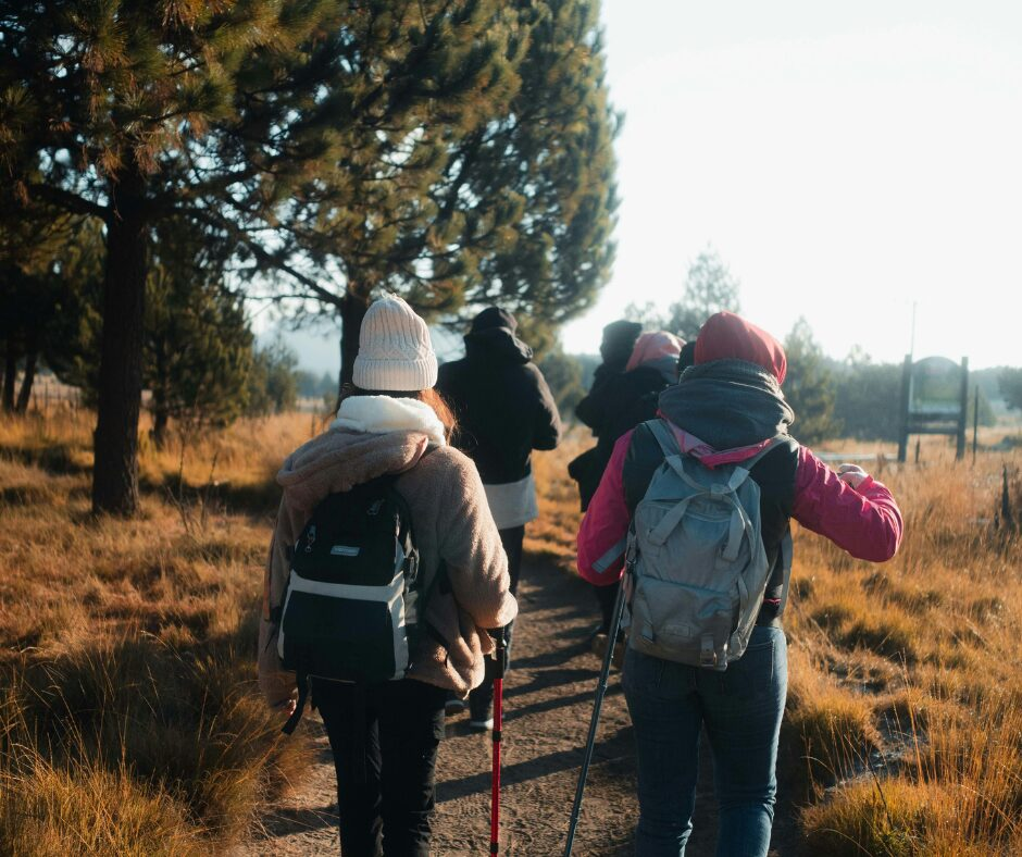 A group of people dressed warmly in coats and hats with hiking sticks walking.