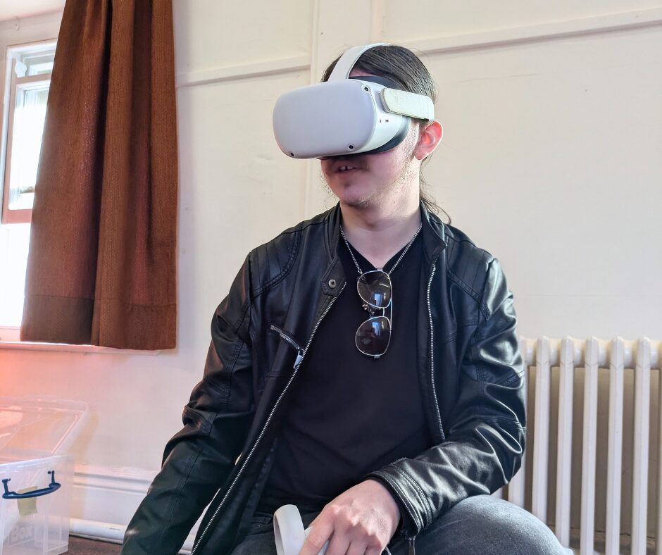 A young man kneeling with a VR headset on.