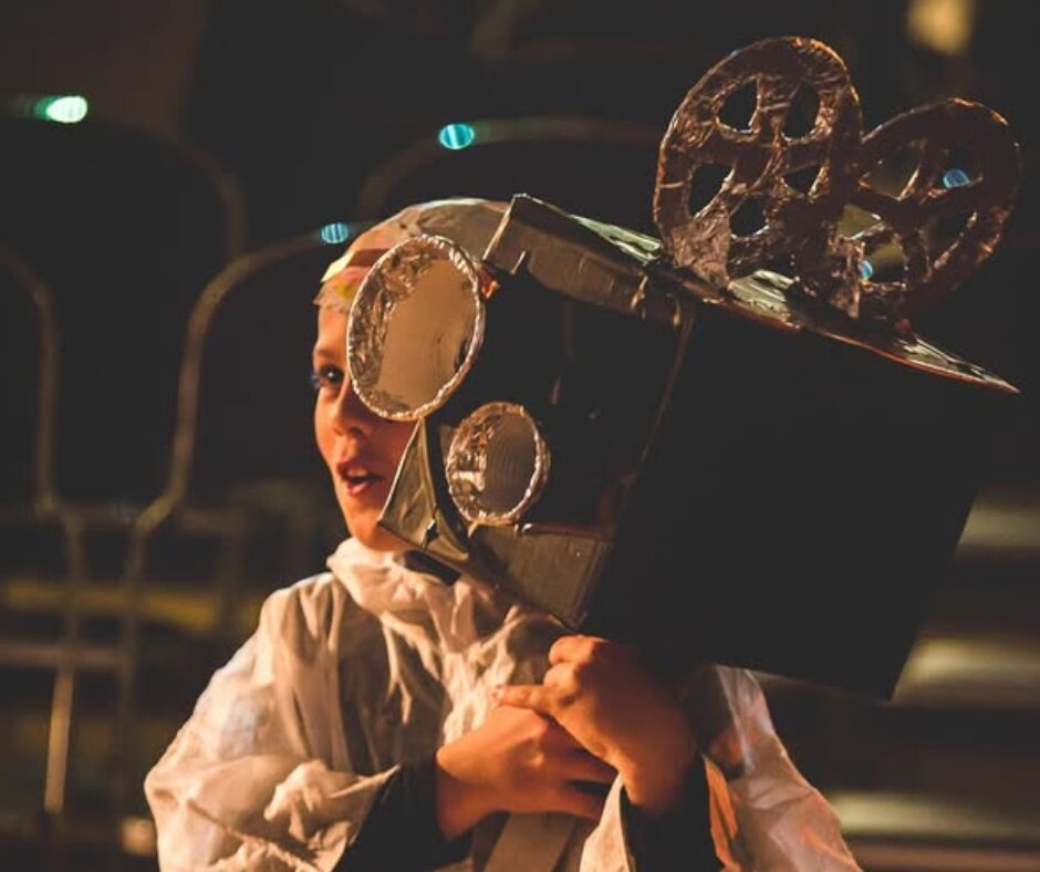 A young boy holding an old style camera prop.