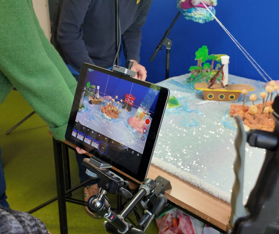 An image of an iPad with stop-frame animation software showing an animation set that includes an island made of potatoes, a ship, a jungle island and a kung fu island.